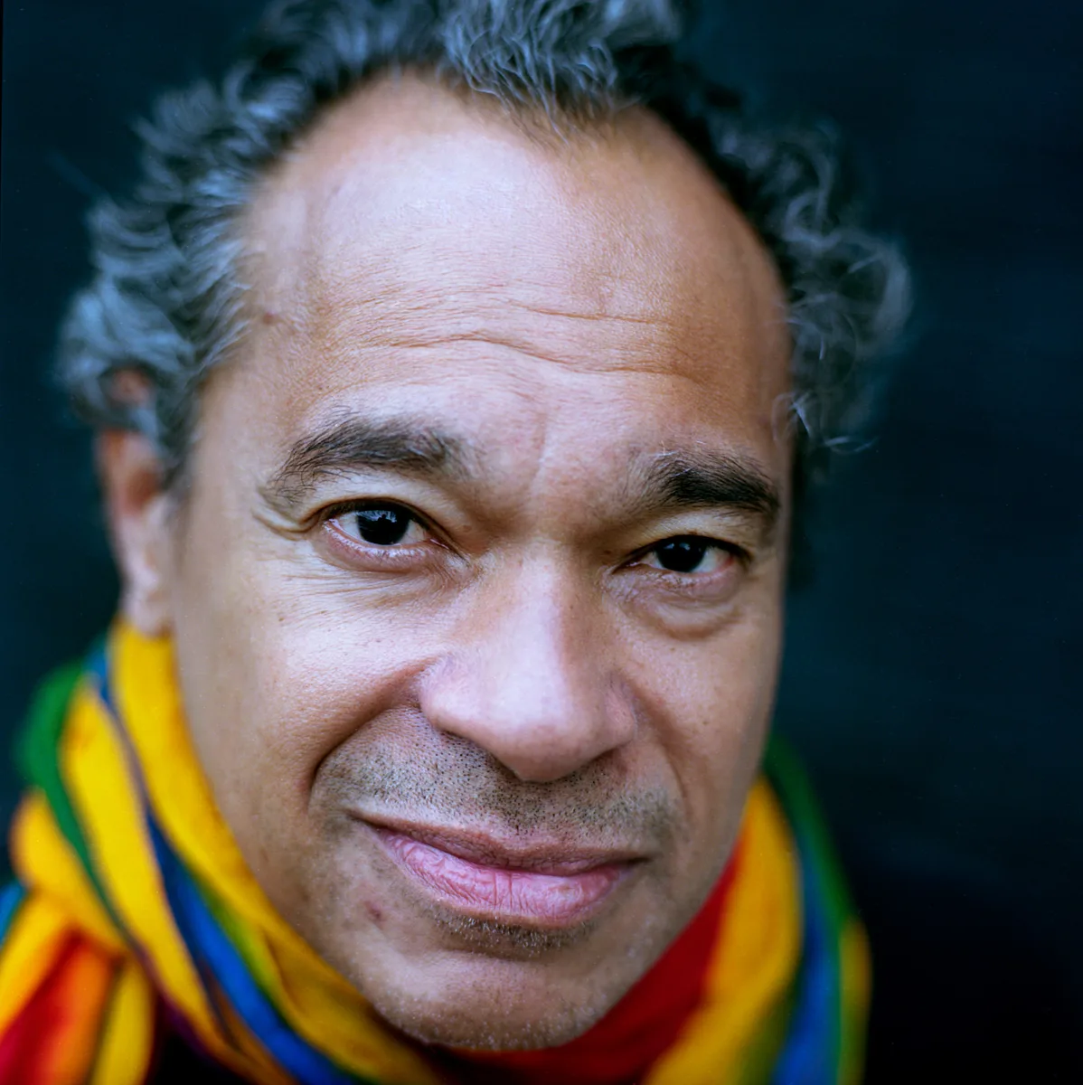 Portrait of Jay Rodriguez Sierra wearing a bright striped scarf.