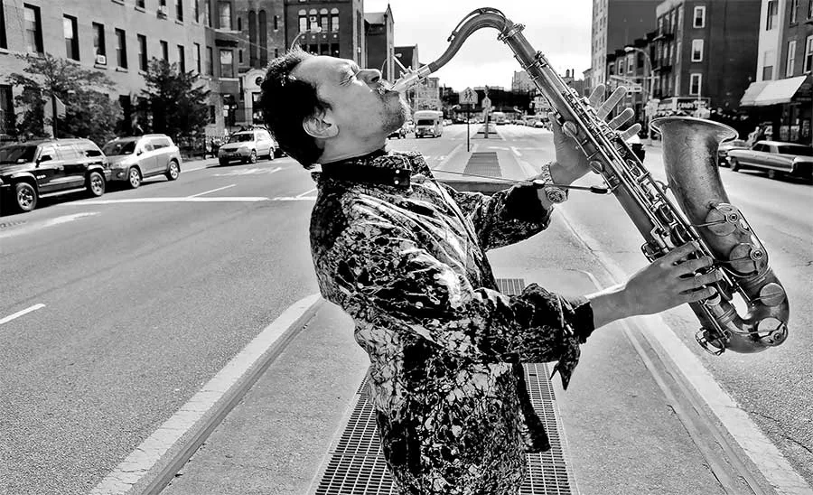 Jay Rodriguez Sierra playing saxophone in the middle of a New York street.